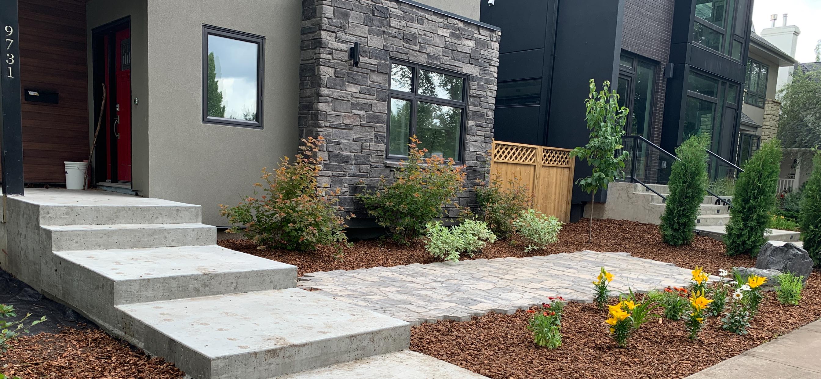 Close-up of front yard mulch garden bed with shrubs, flowers, and concrete steps